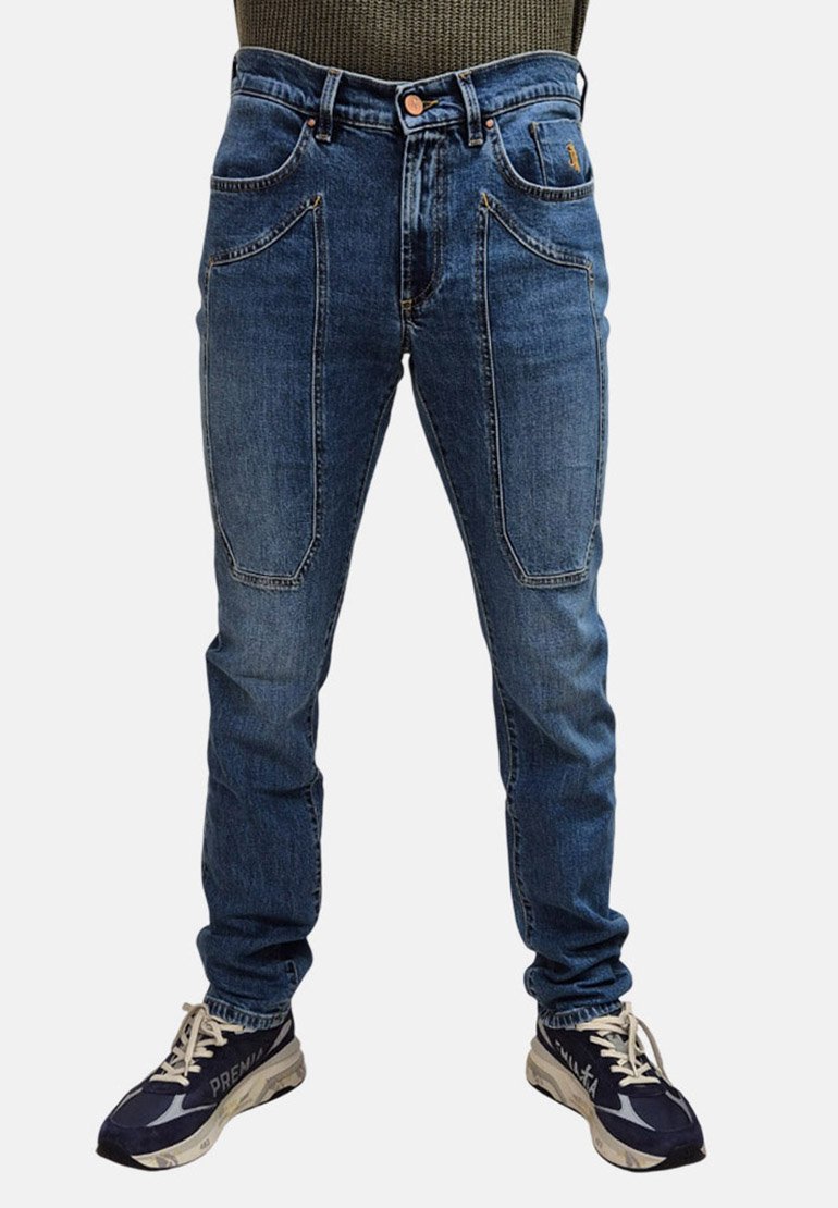 Jeans in denim blu con una vestibilità slim, dotati di due tasche frontali e dettagli di cucitura sottili. Abbinati a scarpe da ginnastica scure.