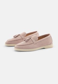 Roze suède loafers met een franjes accent, platte crèmekleurige zool, ronde neus en gestikte details langs de rand.