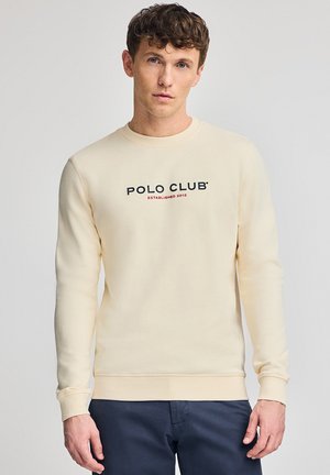 Pullover crema chiaro realizzato in tessuto morbido. Presenta maniche lunghe, un collo rotondo e un logo stampato "POLO CLUB" con l'anno di fondazione sottostante.
