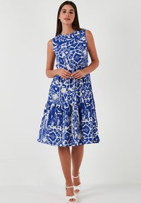Blue and white patterned sleeveless dress with a flared skirt, featuring a round neckline and gathered detail at the waist.