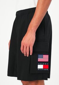 Boxeri de baie negri, cu un cusătura elastică la talie, buzunare laterale și un patch cu steagul american și logo-ul brandului pe piciorul stâng.