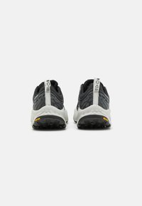 Scarpe da atletica nere e grigie con una tomaia testurizzata a motivo ondulato, dettagli bianchi sul tallone e logo Vibram sulla suola.