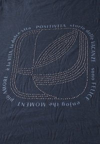 Marineblåt stof med et struktureret mønster; prydet med hvid tekst og dekorative sølvnitter, der danner et geometrisk design og bogstaver.