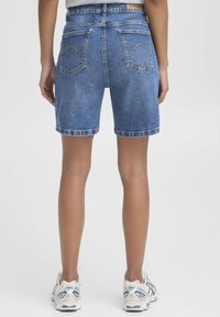 Shorts in denim di un blu chiaro con risvolti, dotati di due tasche posteriori e cuciture a contrasto. Etichetta attaccata visibile in vita.