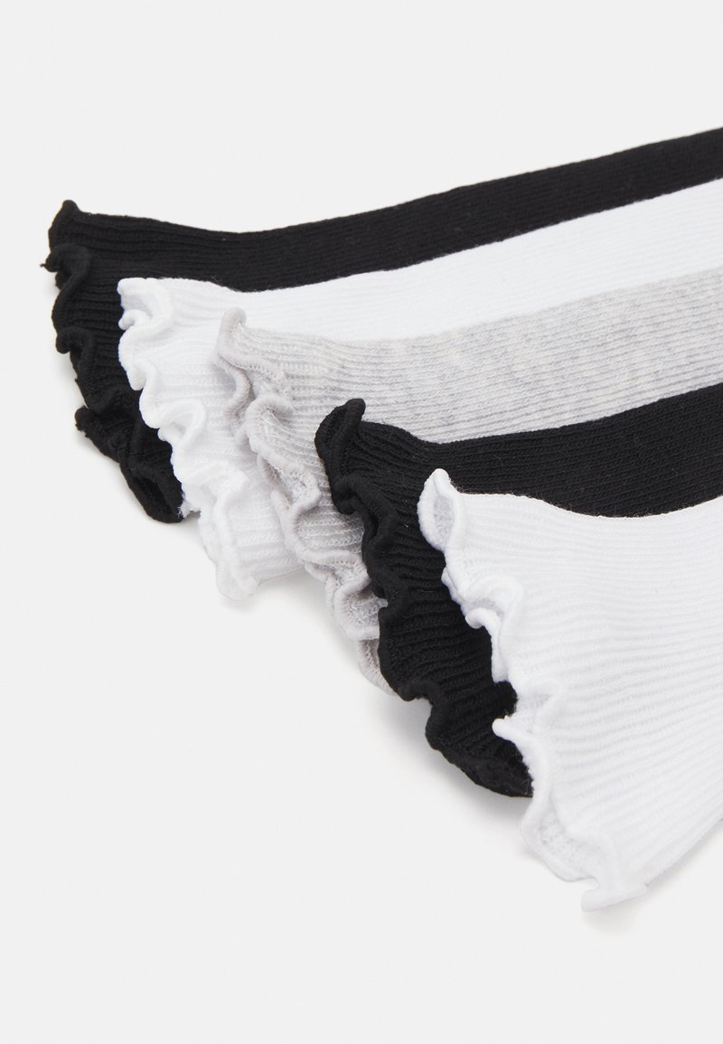 Calcetines a rayas en tejido acanalado negro, blanco y gris con un borde rizado. El diseño incluye tres secciones distintas con bloques de color.