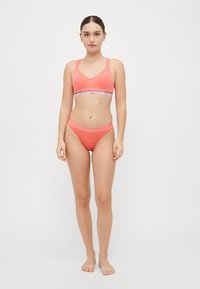 Coral bikini set featuring a V-neck bralette with adjustable straps and a matching bikini bottom. Both have elastic band detailing.