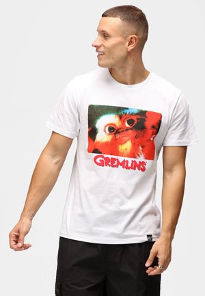 Hvid bomulds t-shirt med et stort farverigt Gremlins grafik. Korte ærmer med afslappet pasform, rund halsudskæring og sort label detalje.