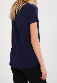 Marinblå t-shirt med kort ärm i mjuk bomull, med rund hals och avslappnad passform, sedd bakifrån med minimal detaljering.