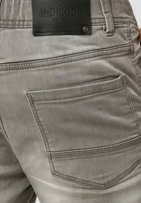 Grijze katoenen broek met een gladde textuur, voorzien van een achterzak en een zwartleren merklabel met reliëftekst.