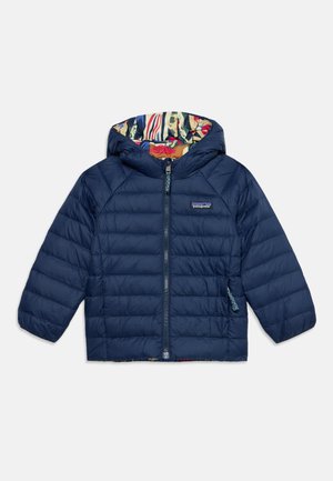 Chaqueta acolchada con capucha en azul marino, cremallera frontal y forro multicolor con estampado visible en el interior de la capucha, logo de Patagonia en el pecho.