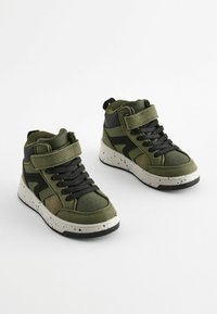 Groene hoge sneakers met zwarte accenten, voorzien van een gestructureerde bovenkant, veterontwerp, klittenbandsluiting en gespikkelde witte zool.