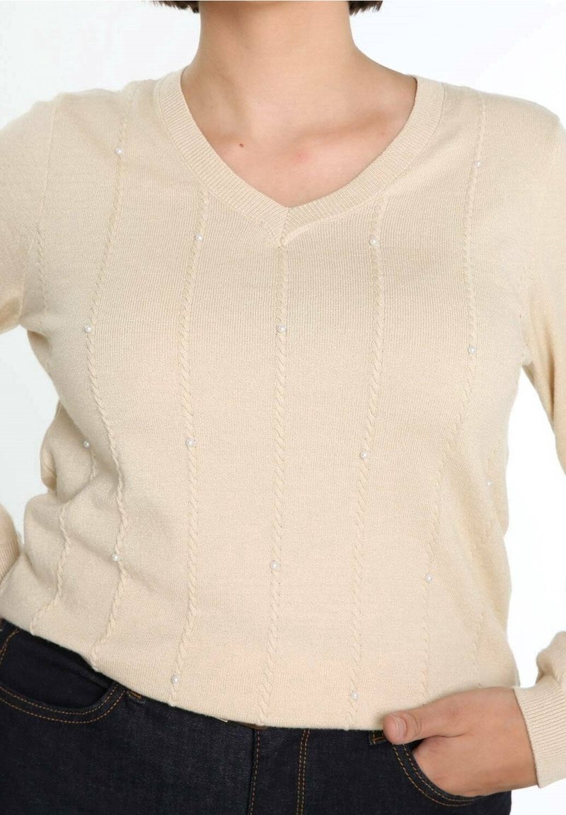 Beżowy sweter z dekoltem w serek, z teksturowanymi pionowymi liniami i małymi perłowymi akcentami, wykonany z dzianiny. Dopasowany krój, długie rękawy.