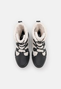 Botas de invierno en blanco y negro con forro de peluche y cordones tipo toggle, vistas desde arriba sobre un fondo liso.