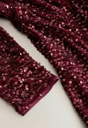 Burgunderfarbener, mit Pailletten besetzter Stoff mit einer weichen Textur, ausgestattet mit eng zusammenliegenden, runden Pailletten. Die Ärmel sind mit Bündchen versehen, was dem Design zusätzliche Details verleiht.
