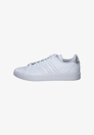 Baskets basses blanches Adidas avec bandes latérales perforées, lacets à l'avant et languette de talon grise sur fond blanc.