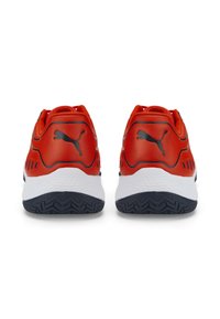 Zapatillas deportivas rojas con parte superior de material sintético liso, media suela blanca y suela de goma negra texturizada. Presenta un logo negro de Puma en el talón.