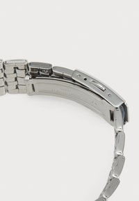 Bracelet de montre en acier inoxydable argenté avec un design à maillons. Il dispose d'une fermeture rabattable et d'une finition lisse et polie. Apparence simple et élégante.