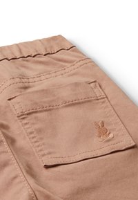 Růžové bavlněné šortky mají zadní kapsu s malým vyšitým Designem králíčka a viditelnými stehy po okrajích.