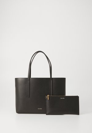 Borsa a tote nera con due manici, abbinata a una pochette con zip coordinata. Entrambi presentano il logo Calvin Klein impresso in argento.