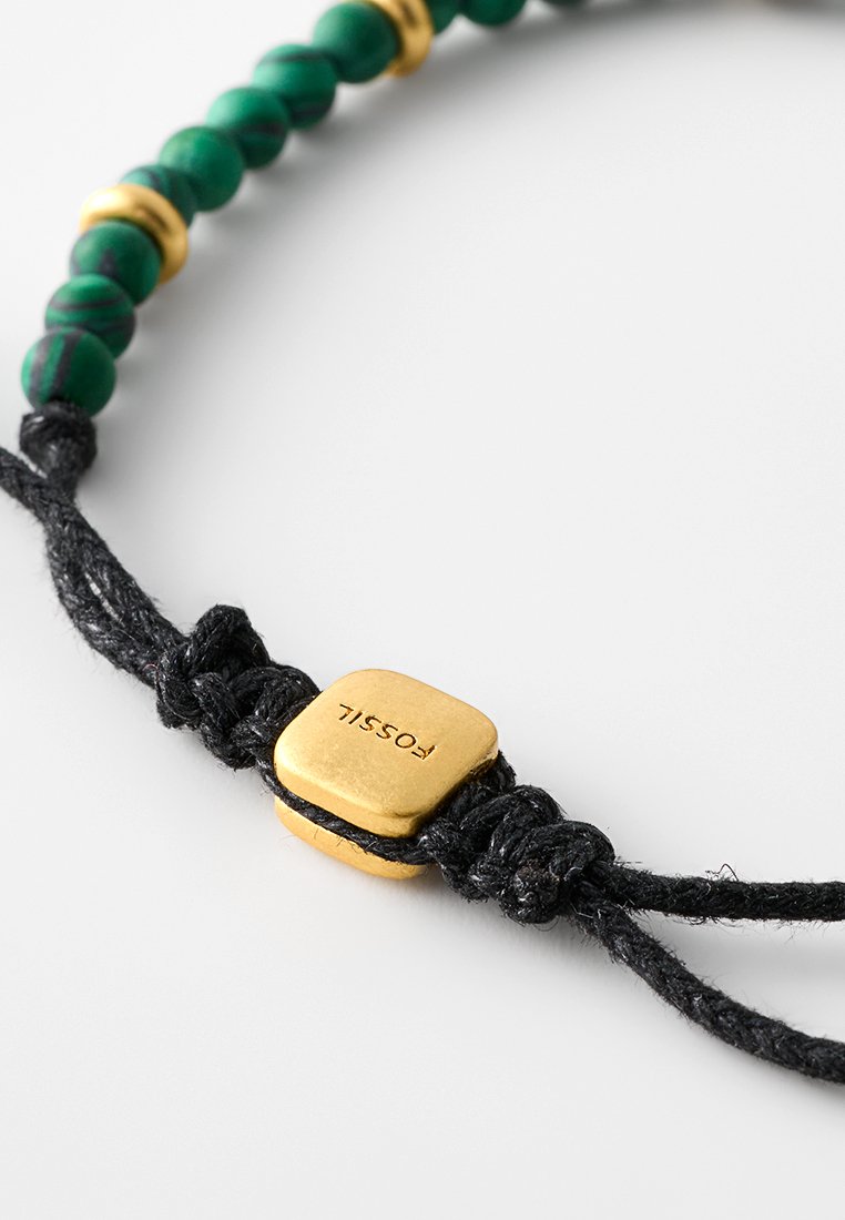 Bracelet ajustable avec des perles de malachite verte, des accents métalliques dorés et un cordon noir tissé avec un charme doré de marque.