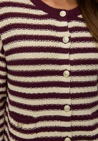 Cardigan lavorato a maglia con righe orizzontali bordeaux e crema, dotato di sei bottoni decorativi in argento e due tasche frontali. Tessuto texturizzato.