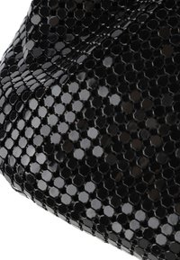 Borsa nera con un motivo esagonale e una superficie lucida e texturizzata. Il materiale appare liscio e brillante, con una forma strutturata.