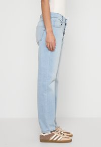 Hellblaue Jeans aus Denim mit einer lässigen Passform, ausgestattet mit einem Reißverschluss, fünf Taschen und subtilen Nähdetails für Struktur.