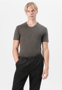 Gray ribbed t-shirt with a round neckline, fitted design, paired with black, elastic-waist, straight-leg pants. Smooth texture.