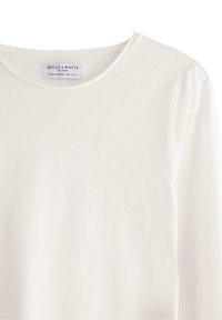 Maglietta bianca a maniche lunghe con scollo rotondo e texture morbida e liscia. Etichetta visibile sul colletto con la scritta "HOLLY & WHYTE."