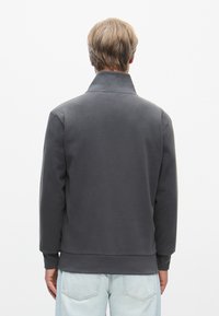 Grå genser med høy krage, ribbede mansjetter og nederkant. Laget av myk stoff, har et ensfarget design og en avslappet passform.