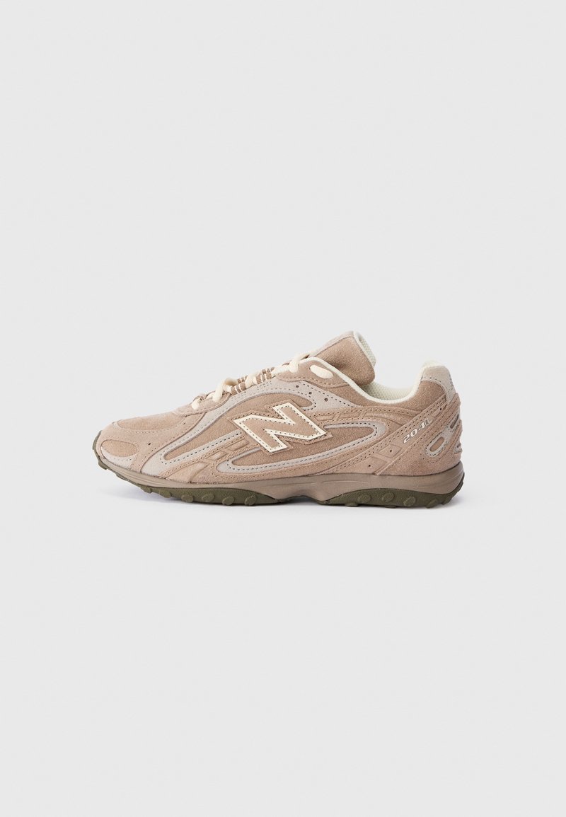 Beige αθλητικά παπούτσια New Balance 2040 με σουέτ επάνω μέρος, κρεμ λουριά και σκούρο πράσινο υφή κάτω μέρος, εμφανίζονται από το πλάι σε άσπρο φόντο.
