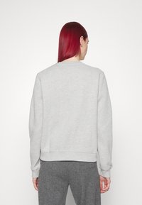 Šedá mikina s dlouhými rukávy a kulatým výstřihem. Má řasené manžety a lem. Měkká textura, jednobarevný design a žádné viditelné vzory.