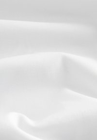 Tela blanca con una textura suave, mostrando pliegues y arrugas sutiles. El material parece ligero y transpirable, sin ningún patrón.