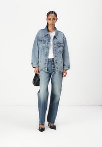Jeansjakke, lys vask, oversized passform. Hvit topp, falmet blå rett jeans. Svart veske og spisse hæler fullfører antrekket.