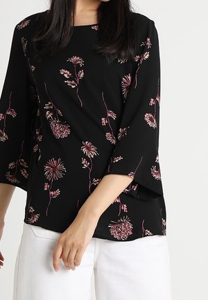 Blusa nera con maniche a tre quarti, decorata con motivi floreali rosa. Realizzata in materiale morbido, presenta un collo rotondo e una vestibilità ampia.