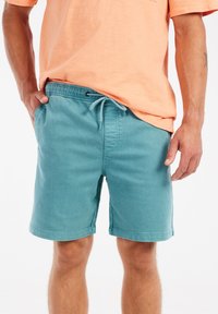 Turquoise stoffen shorts met een elastische tailleband en trekkoord, voorzien van zijzakken en een eenvoudige gestikte zoom.