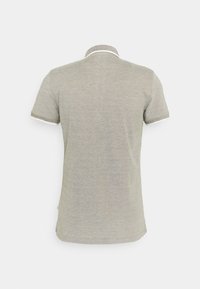 Kortermet polo skjorte i lysegrått stoff, med kontrastfarge på kragen og mansjettene, teksturert kant, rett nederkant og ingen synlige logoer.