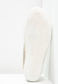 Semelle blanche de basket avec motif de bande ondulée, taille 37 indiquée à l’intérieur d’un motif circulaire près de la zone de la plante du pied.