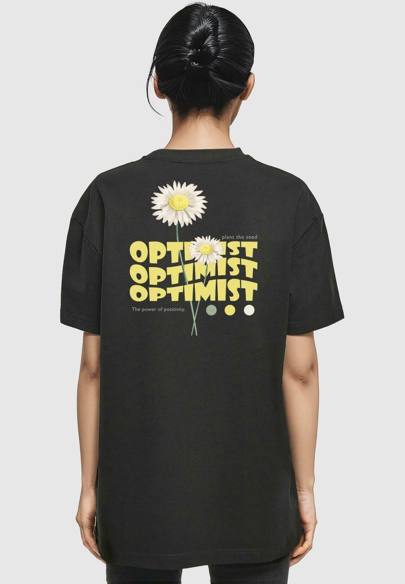 Černé bavlněné tričko s grafickým designem bílých sedmikrásek a textem "OPTIMISTA" v žluté barvě. Volný střih, kulatý výstřih, krátké rukávy.