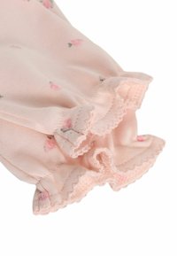 Rosa Stoff mit floralem Muster und gerafftem Saum. Weiche Textur, zarte Nähte und kleine Rose-Motive verleihen dem Design eine besondere Note.