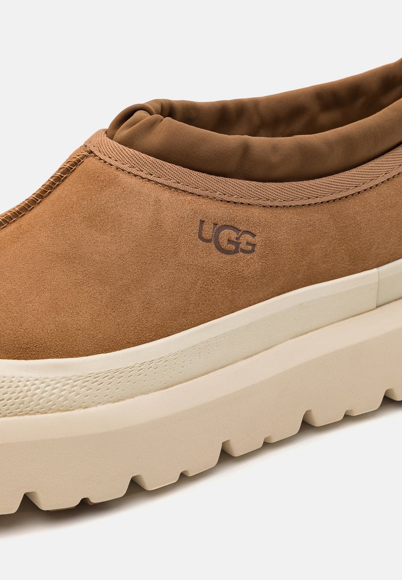 Braune Wildlederschlupfschuhe mit gepolstertem Kragen, beigefarbenem, chunkigem Absatz und geprägtem Logo-Detail. Verfügt über eine strukturierte Gummisohle.