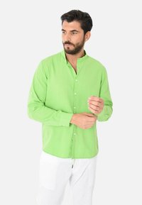 Camicia verde a maniche lunghe con colletto a band, realizzata in tessuto leggero, con una texture liscia e una vestibilità su misura.