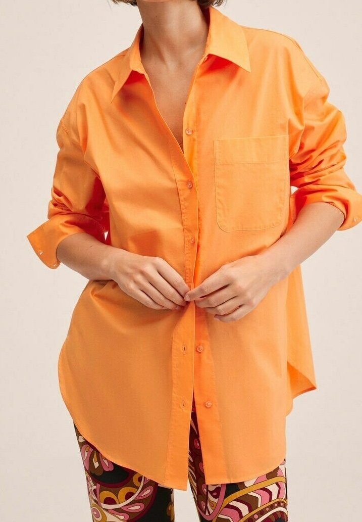 Chemise en coton orange à boutons, manches retroussées, poche poitrine et coupe ample, associée à des leggings à motifs.