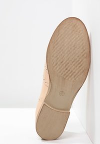 Chaussure en cuir nud avec une surface lisse, un bout rond et un petit talon. La semelle présente un motif de grip texturé et une indication de taille.