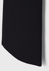 Črna oblačila z gladko teksturo in ukrivljenim robom. Tkanina se zdi lahka in je zasnovana za tesno prileganje. Minimalističen dizajn.