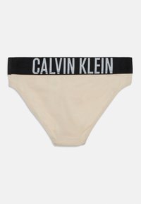 Beige bomullskalsonger med ett svart elastiskt midjeband som har "CALVIN KLEIN" i ljusgrå bokstäver. Slät textur, klassisk kalsongform.