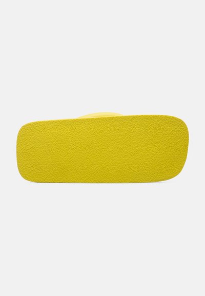 Semelle de sandale en caoutchouc jaune, surface texturée, bords arrondis, design plat, avec une couleur vive et un minimalisme dans les détails.
