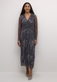 Duga siva haljina s dubokim dekolteom, prozirnim dugim rukavima i ukrasima od šljokica u obliku cvijeća. Glatka tkanina s vertikalnim prugama.