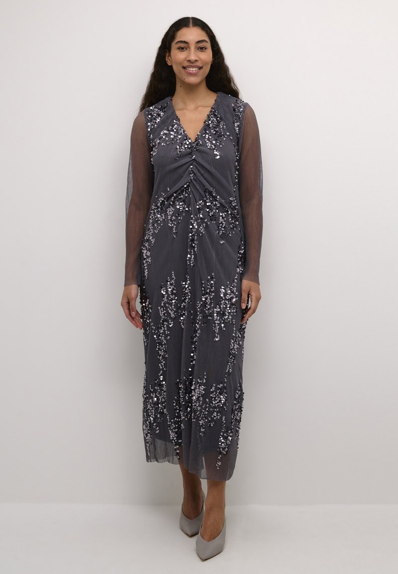 Duga siva haljina s dubokim dekolteom, prozirnim dugim rukavima i ukrasima od šljokica u obliku cvijeća. Glatka tkanina s vertikalnim prugama.