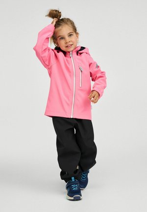 Giacca impermeabile rosa con cerniera, dettagli neri e cappuccio. Abbinata a pantaloni neri e scarpe da atletica blu con dettagli turchesi.